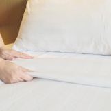 lady-hands-set-up-white-bed-sheet-in-hotel-room